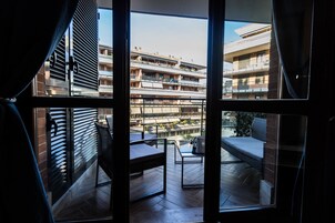 Un balcón con vistas a edificios de varios pisos, una mesa y dos sillas.