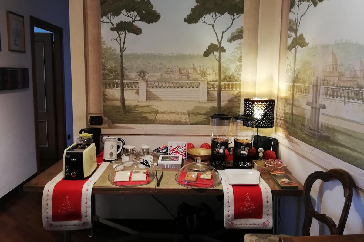 A dining area with a table set for tea, a coffee maker, and a decorative lamp.