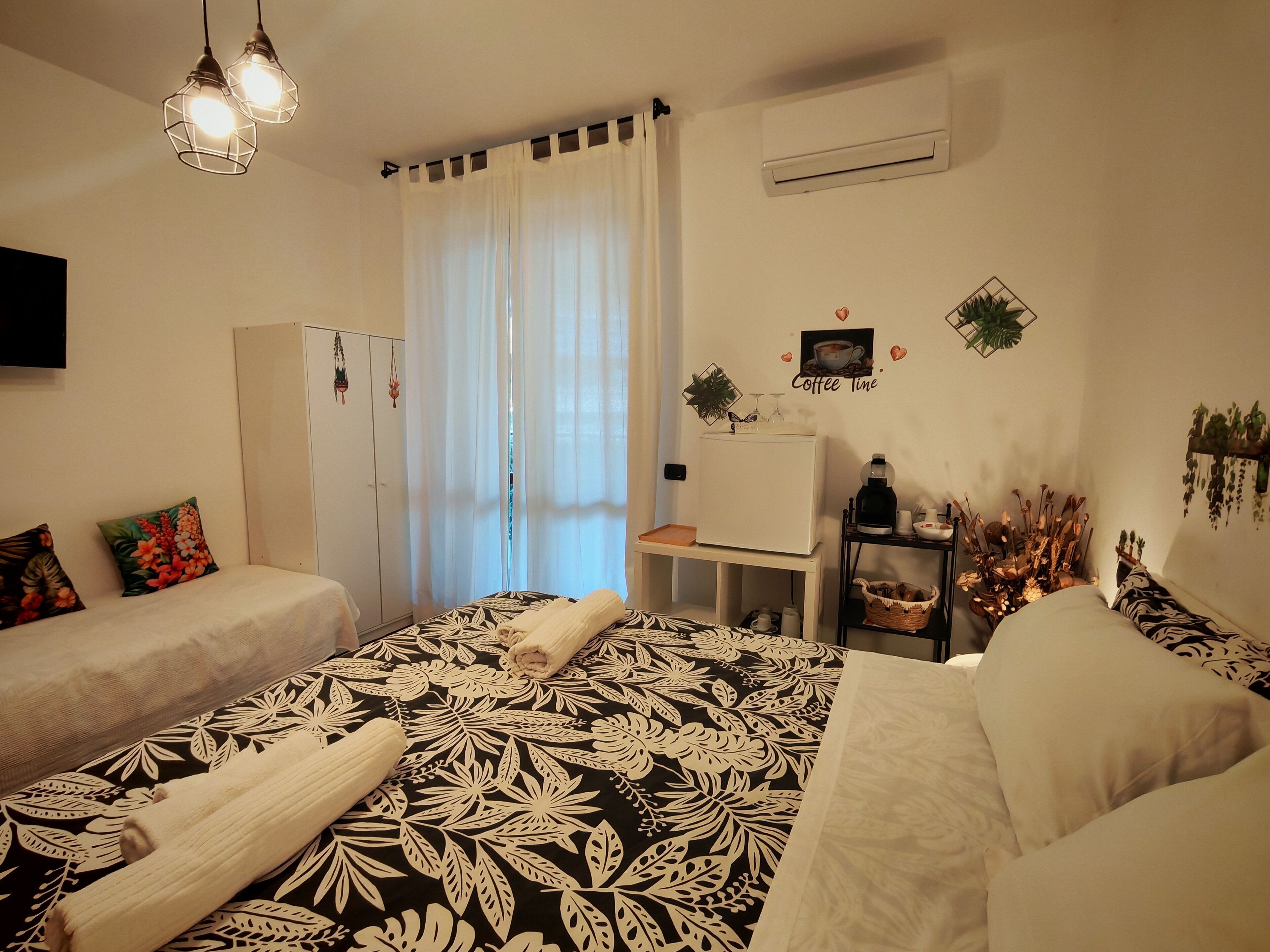Une chambre avec deux lits, une armoire, un bureau avec une machine à café et un climatiseur fixé au mur.