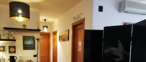 Una cocina con armarios de madera, un refrigerador negro con un diseño de dragón, una lámpara colgante y un aire acondicionado instalado en la pared.