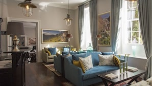 A well-lit living room with a sofa set, a coffee table, and a dining area with a table and chairs. - Mantis St Helena (Jamestown)