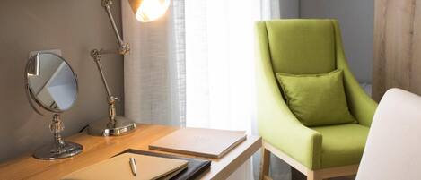 A desk with a lamp, a mirror, a notebook, and a laptop.