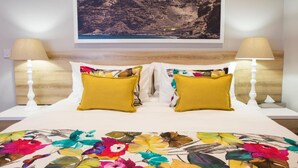 A bed with two yellow pillows, a floral bedspread, and a framed picture of a mountain on the wall. - Mantis St Helena (Jamestown)