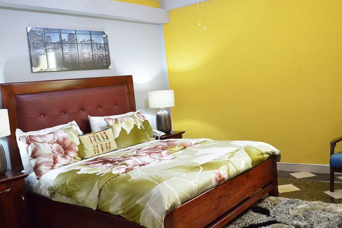 A bedroom with a bed, two bedside tables, a chair, and a wall-mounted picture.