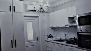 A modern kitchen with stainless steel appliances, a marble countertop, and a chandelier. - Royal Haveala Apartments (Accra)