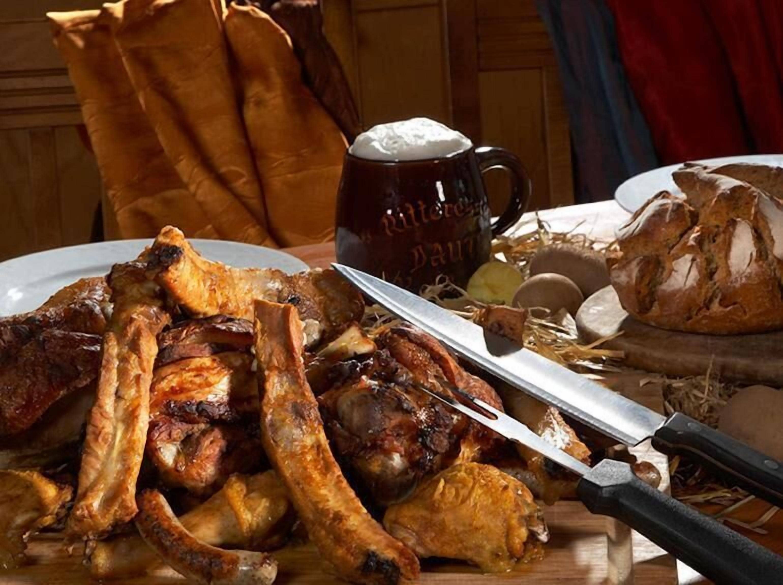 A table with roasted meat, a beer mug, and a loaf of bread.