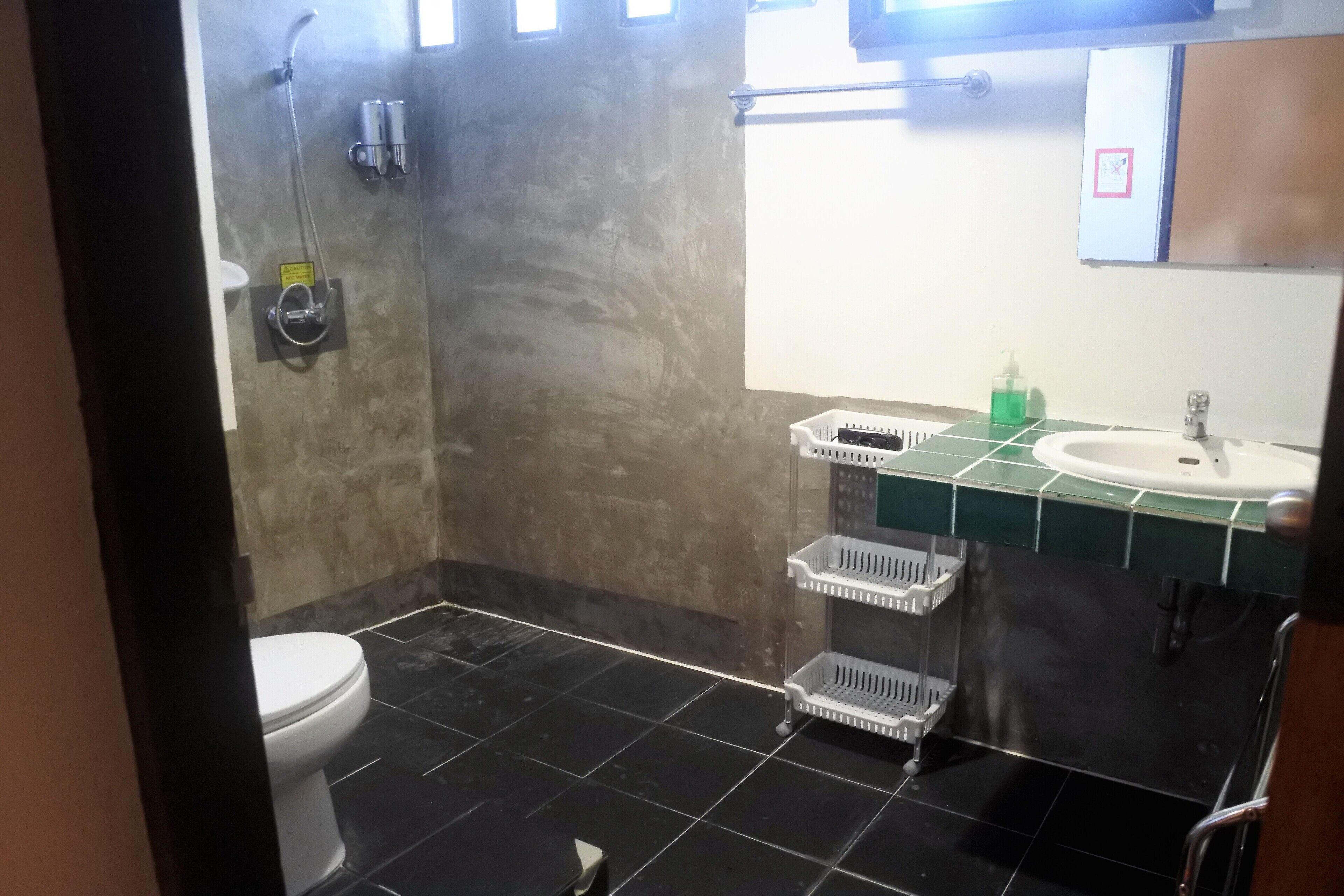 A bathroom with a toilet, a shower, a sink, and a mirror.