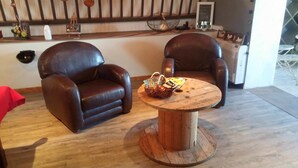Twee leren fauteuils en een houten salontafel in een kamer met een houten vloer en een witte muur.