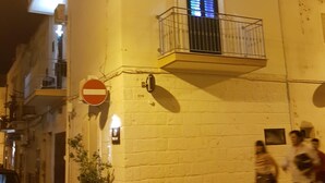 Ein Gebäude mit einem Verbotsschild, einem Balkon mit Metallgeländer und einem Blumentopf auf dem Bürgersteig.