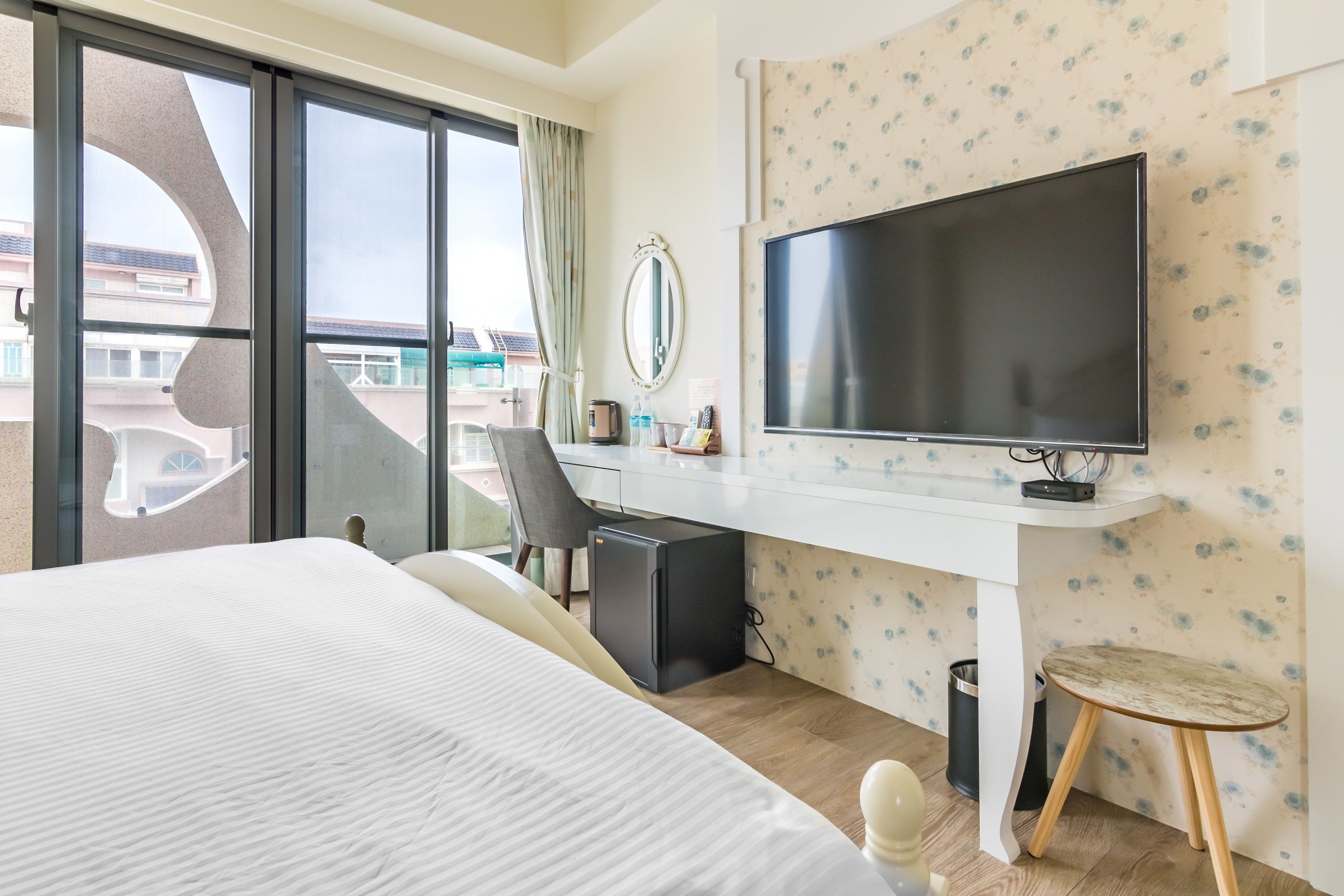 Une chambre d’hôtel avec un grand lit, un bureau avec un ordinateur, une télévision et une vue sur l’extérieur.