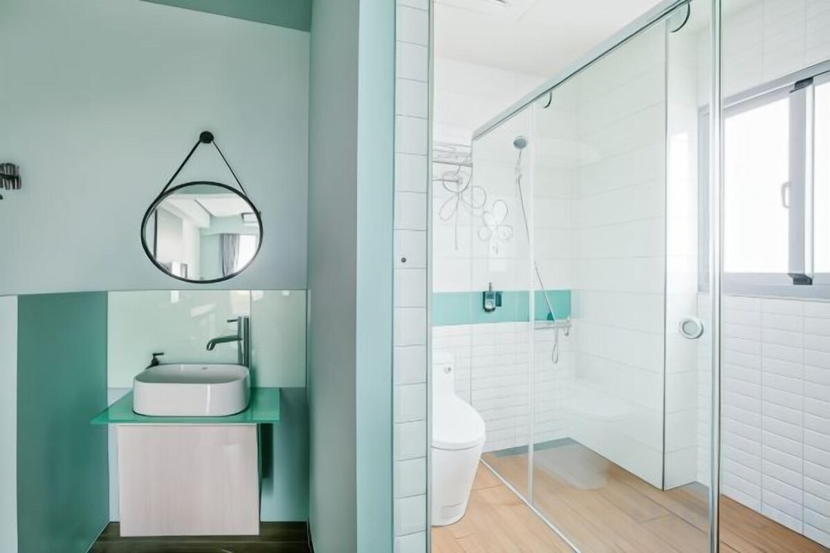 Un baño moderno con cabina de ducha de vidrio, un lavabo blanco y un espejo.