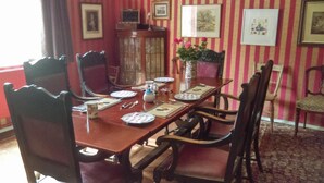 A dining room with a wooden table set for six, surrounded by upholstered chairs. - Orchard Pond Bed & Breakfast (Cambridge)