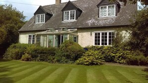 A two-story house with a conservatory, surrounded by well-maintained lawns and dense shrubbery. - Orchard Pond Bed & Breakfast (Cambridge)