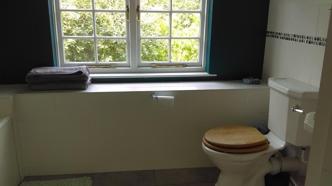 A bathroom with a toilet, a window, and a towel on the windowsill.