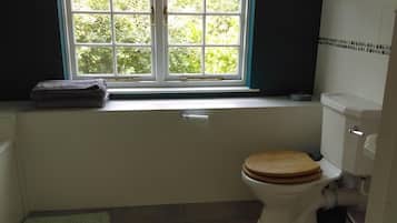 A bathroom with a toilet, a window, and a towel on the windowsill.