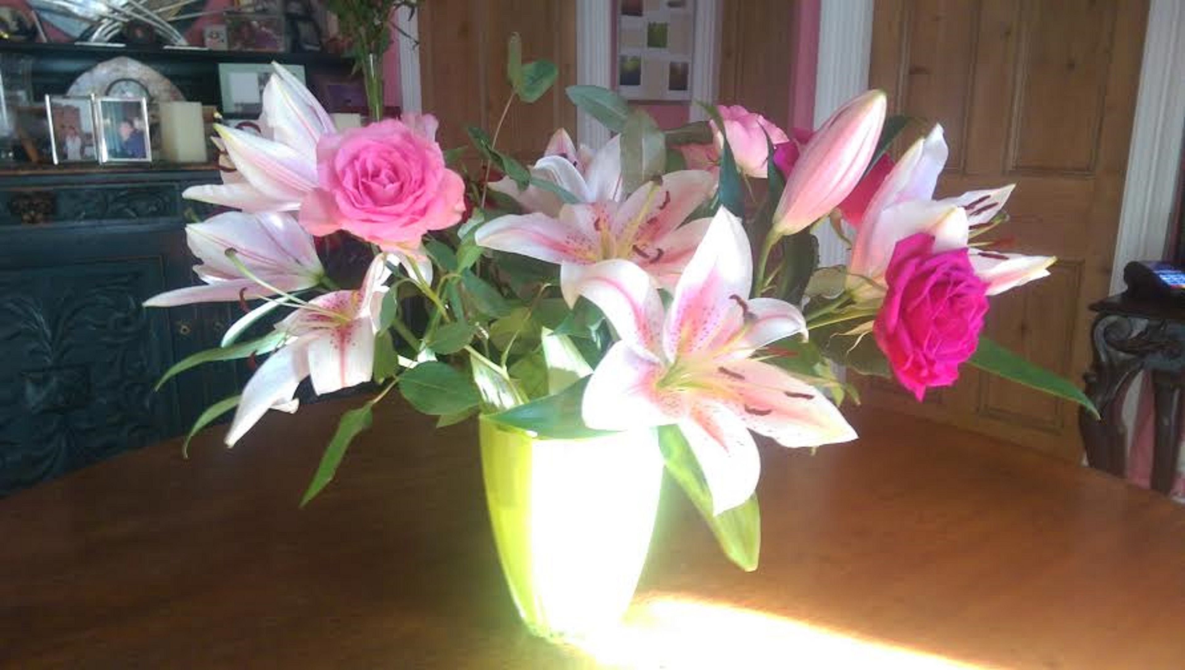 A vase with flowers on a wooden table.