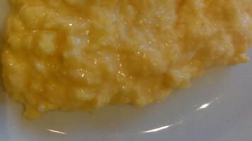 A close-up of a creamy yellow dish, possibly a type of risotto or porridge, on a white plate.