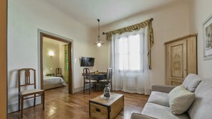 Un salon doté d’un parquet, d’un canapé, d’une table basse, d’un téléviseur et d’un coin repas avec des chaises et une table.