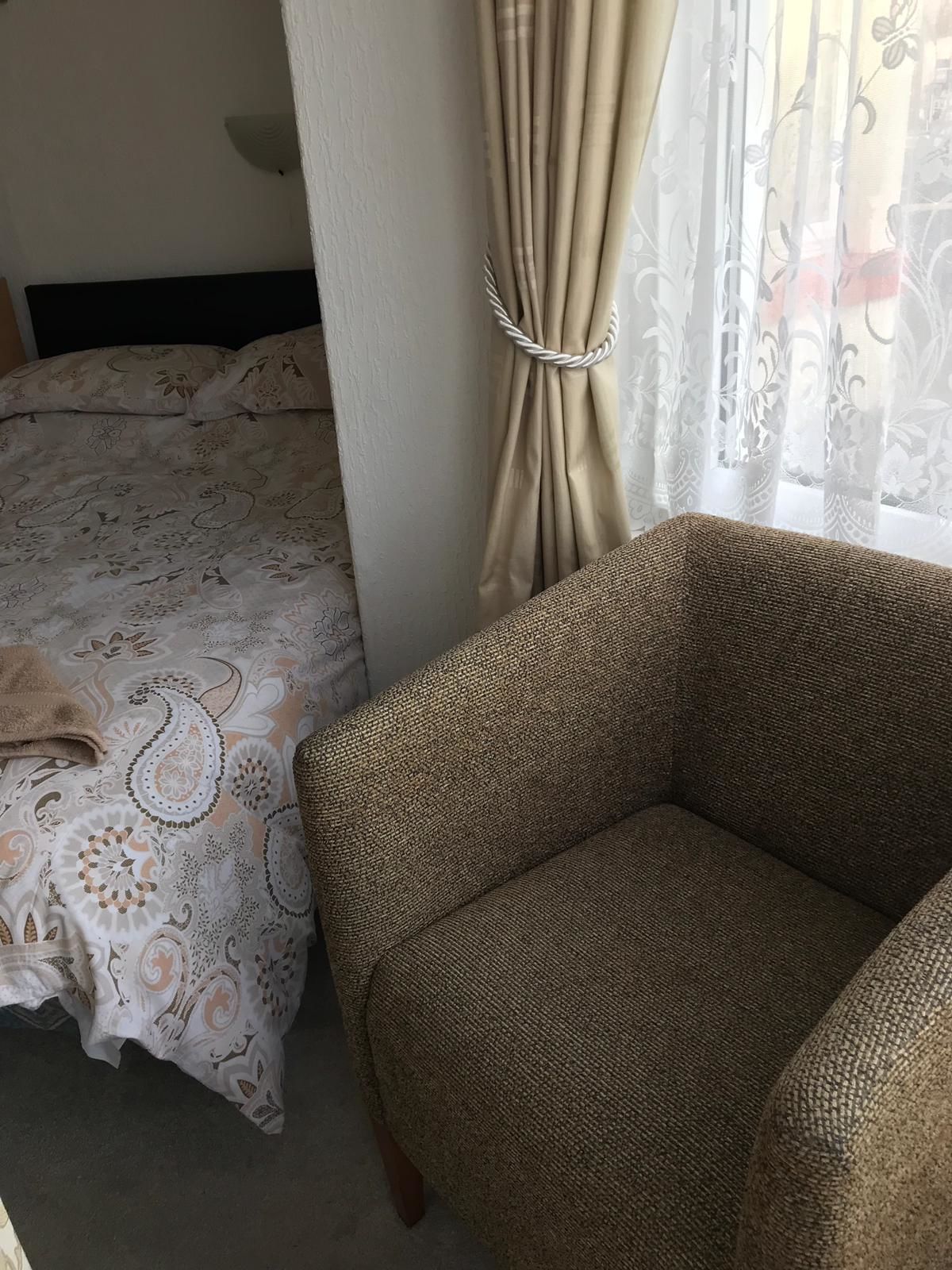 Ein Schlafzimmer mit einem Bett, einem Sessel und einem Fenster mit Vorhängen.