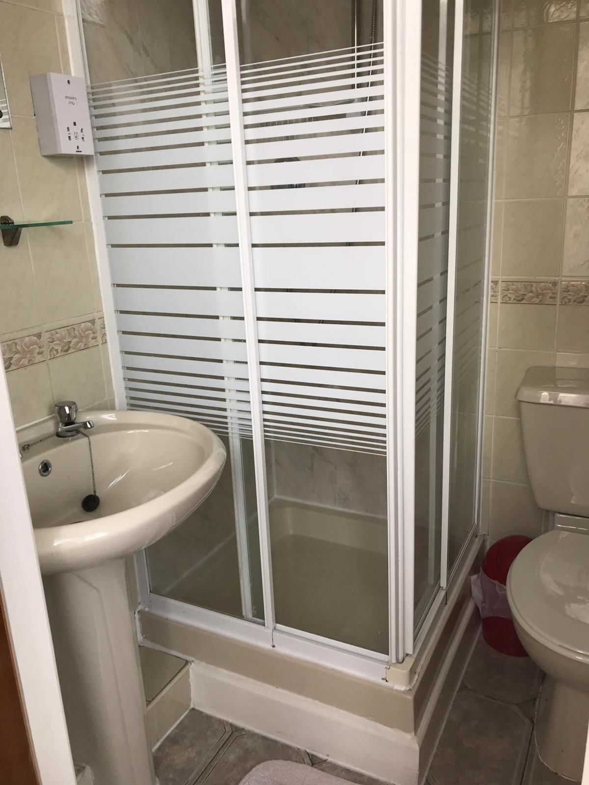 A bathroom with a glass-enclosed shower, a sink, and a toilet.