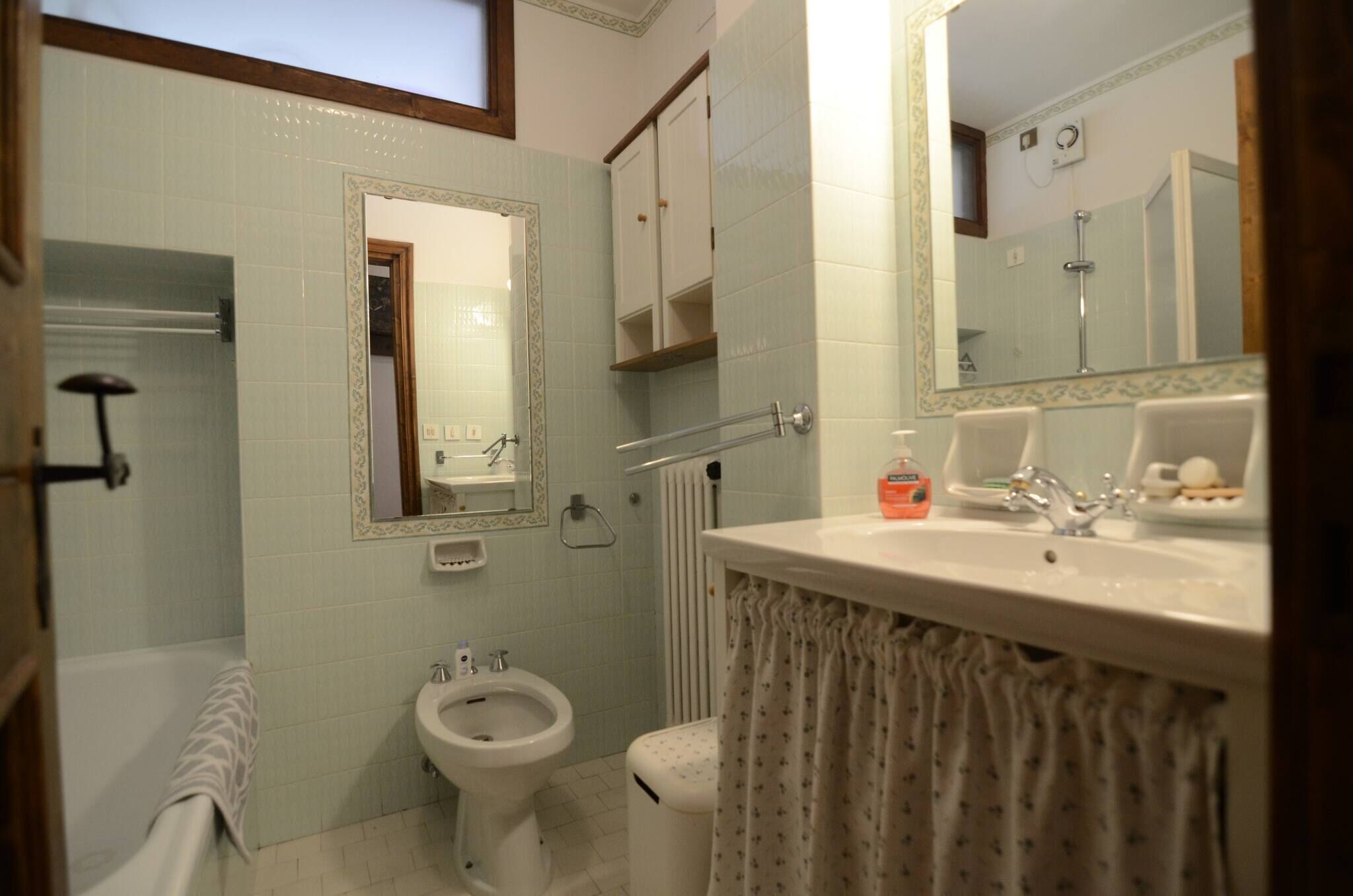 A bathroom with a toilet, bidet, sink, mirror, and towel rack.