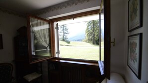 Une pièce avec une grande fenêtre, un radiateur, une chaise et un lit.