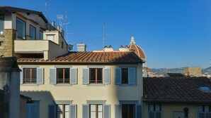 Un immeuble à plusieurs étages, doté d’un toit en tuiles, de nombreuses fenêtres avec volets et d’une structure en forme de dôme sur le toit.