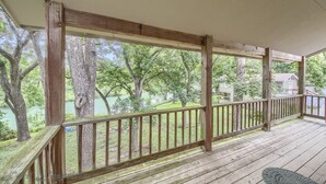 Une terrasse en bois dotée d’une rambarde, qui offre une vue sur un lac et des arbres.