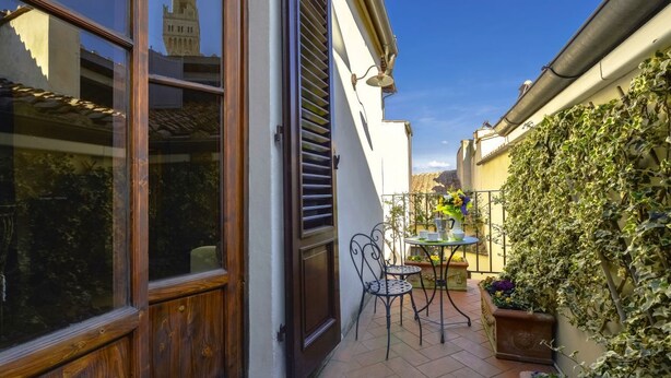 A courtyard with a table and chairs, a window with shutters, and a wall covered in ivy. - Cozy Studio w/ Terrace & Unparalleled Location (Firenze)