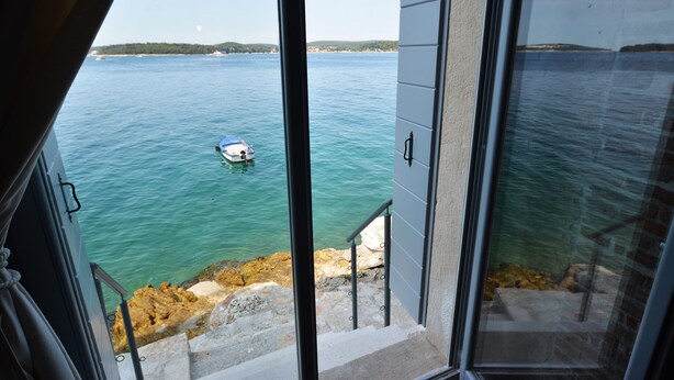 A view from a balcony overlooking a calm sea with a boat anchored nearby. - Arnolongo Apartments (Rovinj)