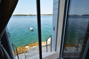 A view from a balcony overlooking a calm sea with a boat anchored nearby. - Arnolongo Apartments (Rovinj)