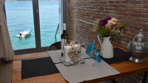 A table with a bottle, a glass, a vase with flowers, and a lantern. - Arnolongo Apartments (Rovinj)