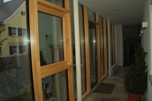 A corridor with wooden-framed glass doors and a potted plant.