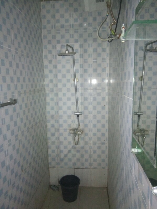 A small, tiled bathroom with a shower and a mirror.