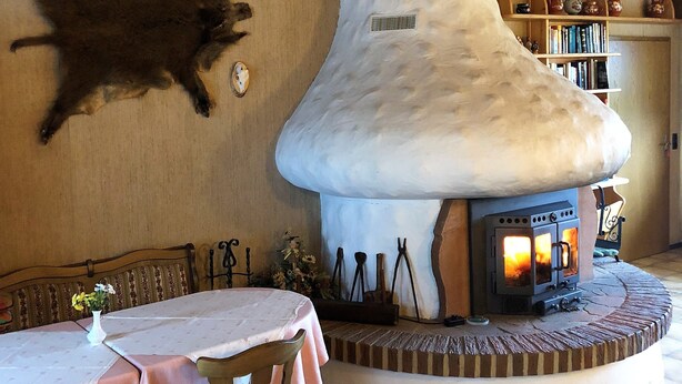 A cozy interior with a stone fireplace, wooden walls, and a dining area with a table and chairs. - Cafe Best Gästezimmer (Erbach)