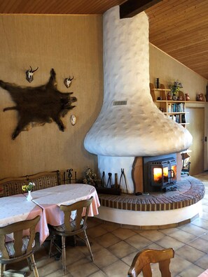 A cozy interior with a stone fireplace, wooden walls, and a dining area with a table and chairs. - Cafe Best Gästezimmer (Erbach)