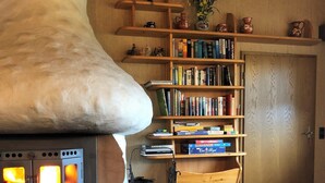 A cozy room with a wood-burning stove, a bookshelf, and a dining area with chairs. - Cafe Best Gästezimmer (Erbach)