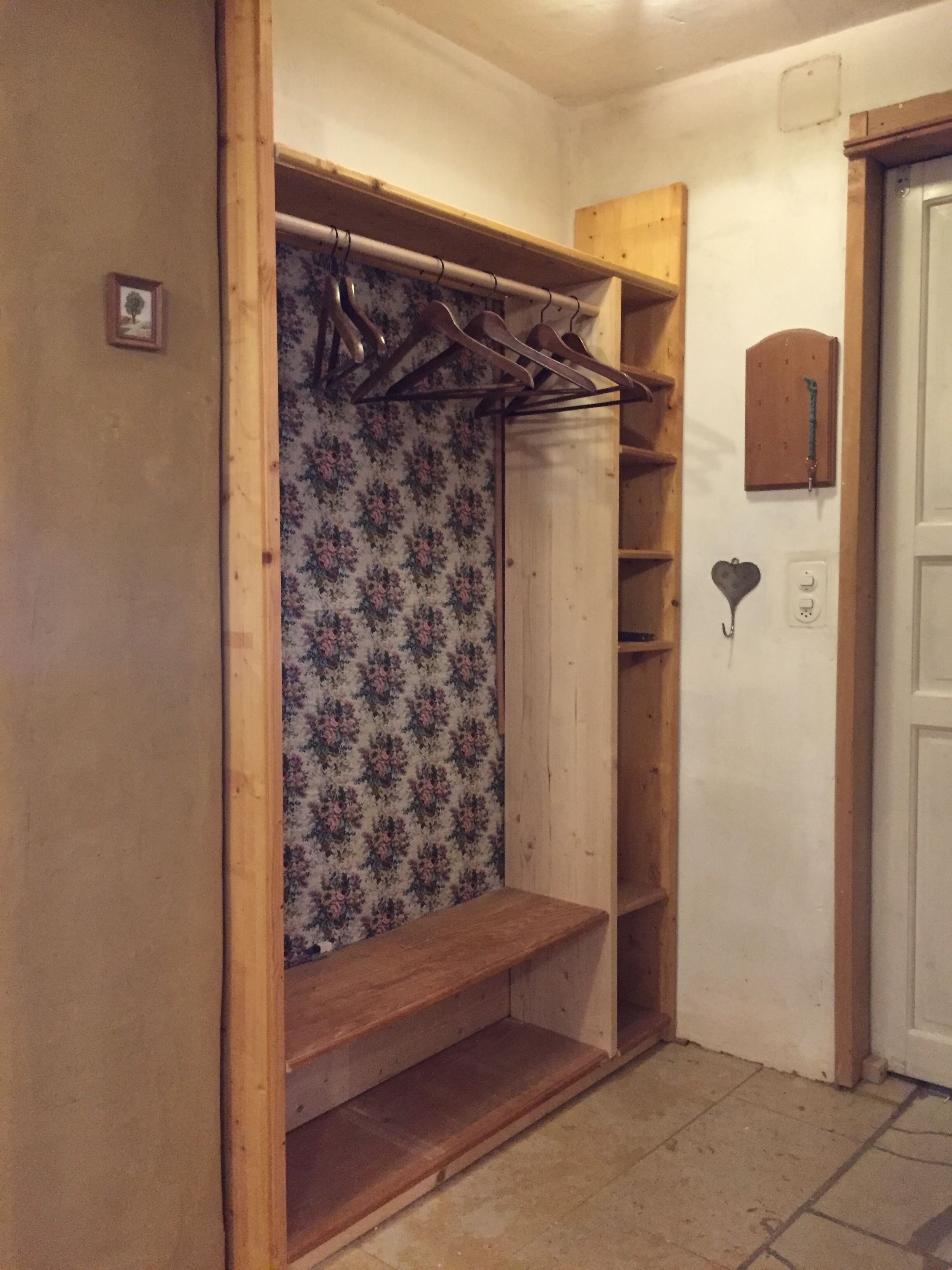 Un dressing avec des étagères en bois, une tringle à vêtements et un papier peint à motifs floraux.