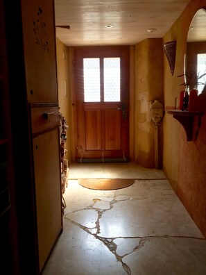 A narrow hallway with a wooden door, a refrigerator, and a stone floor with visible cracks. - Apartment/ flat - Waldenburg (Waldenburg)