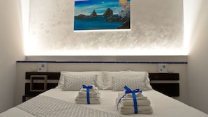 Ein Hotelzimmer mit Bett, Kissen, einem Gemälde und Handtüchern.