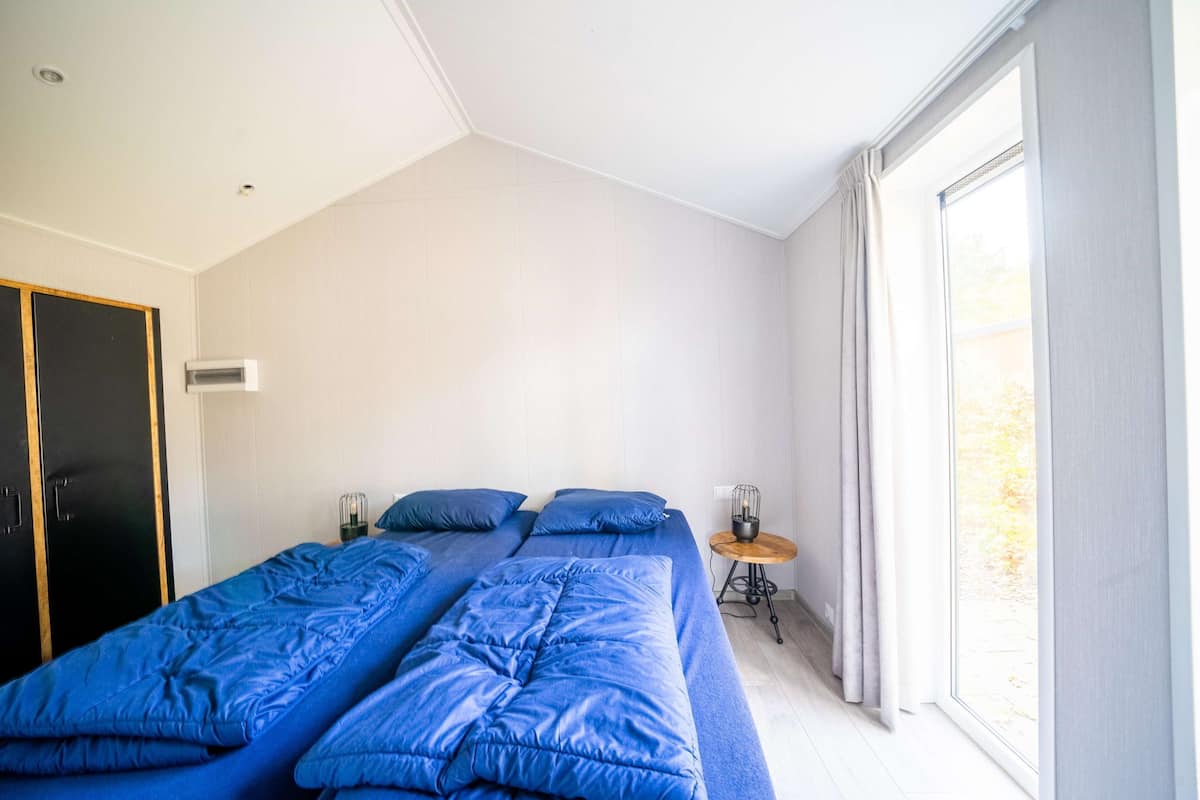 Une chambre à coucher avec un grand lit, une table de chevet, une lampe, une armoire et une fenêtre.