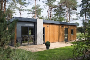 Ein modernes Haus mit einer Fassade aus Holz und Metall, großen Fenstern und einem gepflegten Garten.