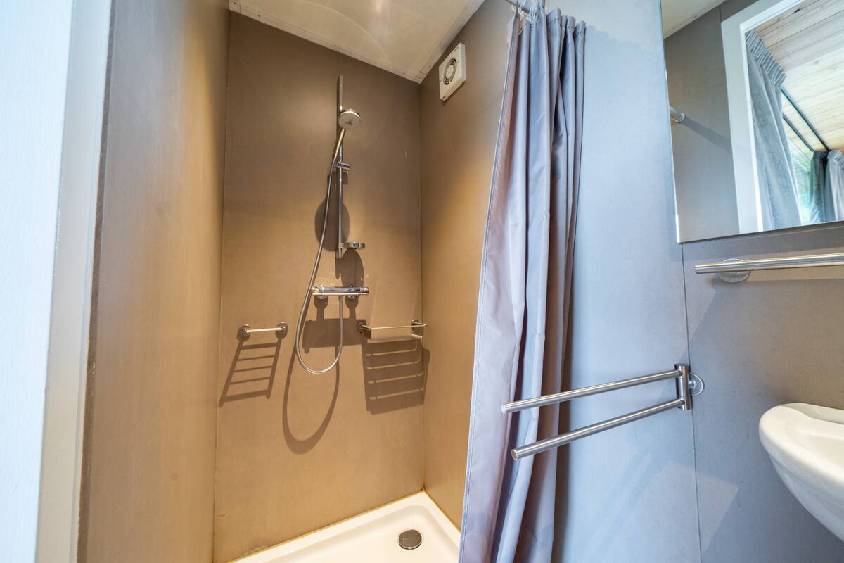Une salle de bain équipée d’une douche, d’un porte-serviettes, de toilettes et d’un miroir.