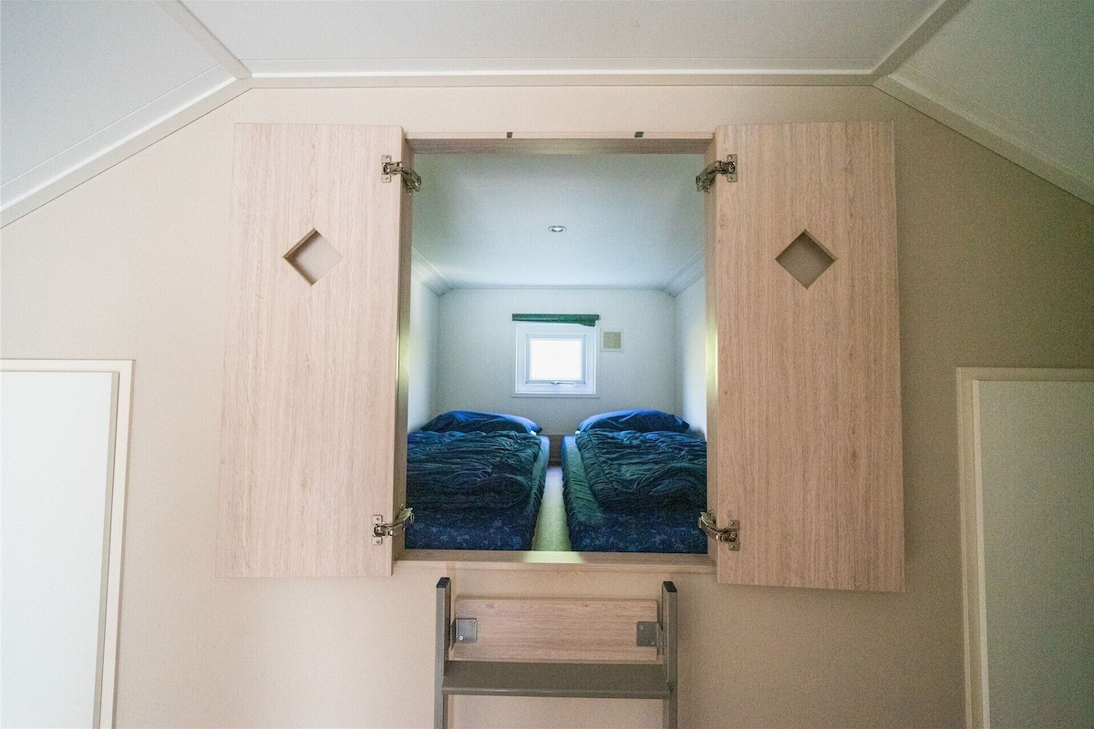 Une chambre avec deux lits, une fenêtre et une porte.