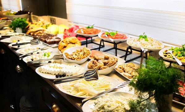 Un buffet proposant une variété de plats, notamment des fromages, des noix et des salades.