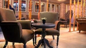 A room with two upholstered armchairs, a round table with a vase, and a wooden chair with a backrest. - Hotel Zade (Erzurum)