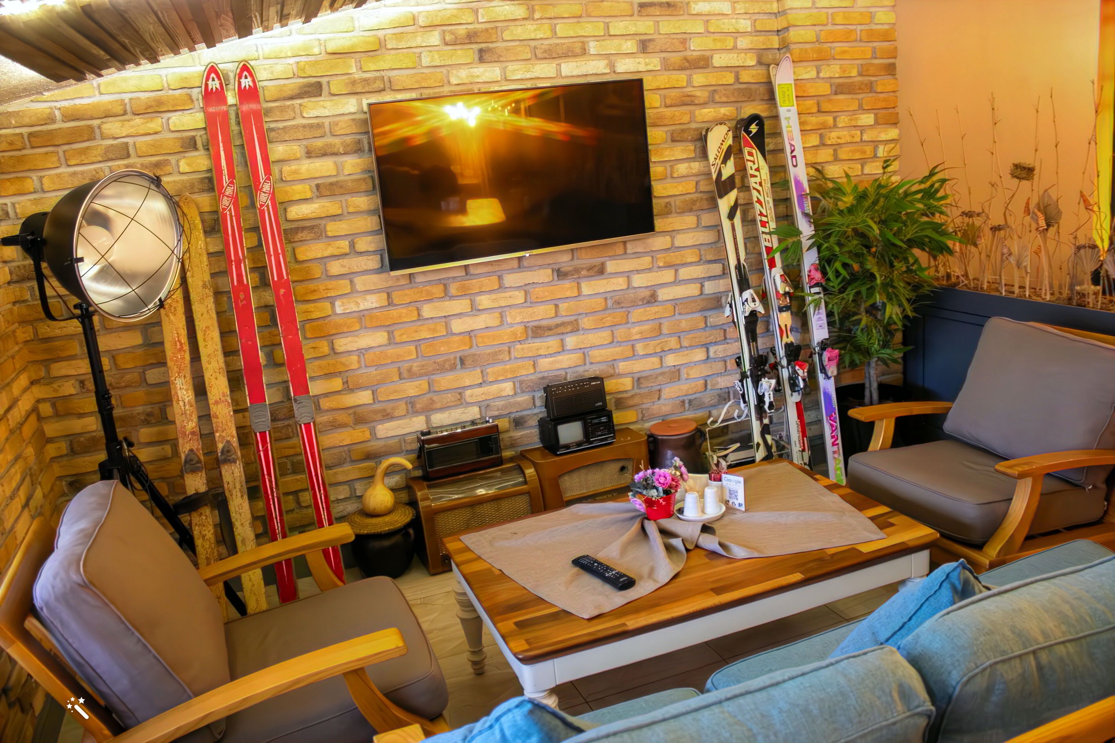 Un salón acogedor con pared de ladrillo, televisor de pantalla plana, mesa de centro de madera y equipo de esquí.