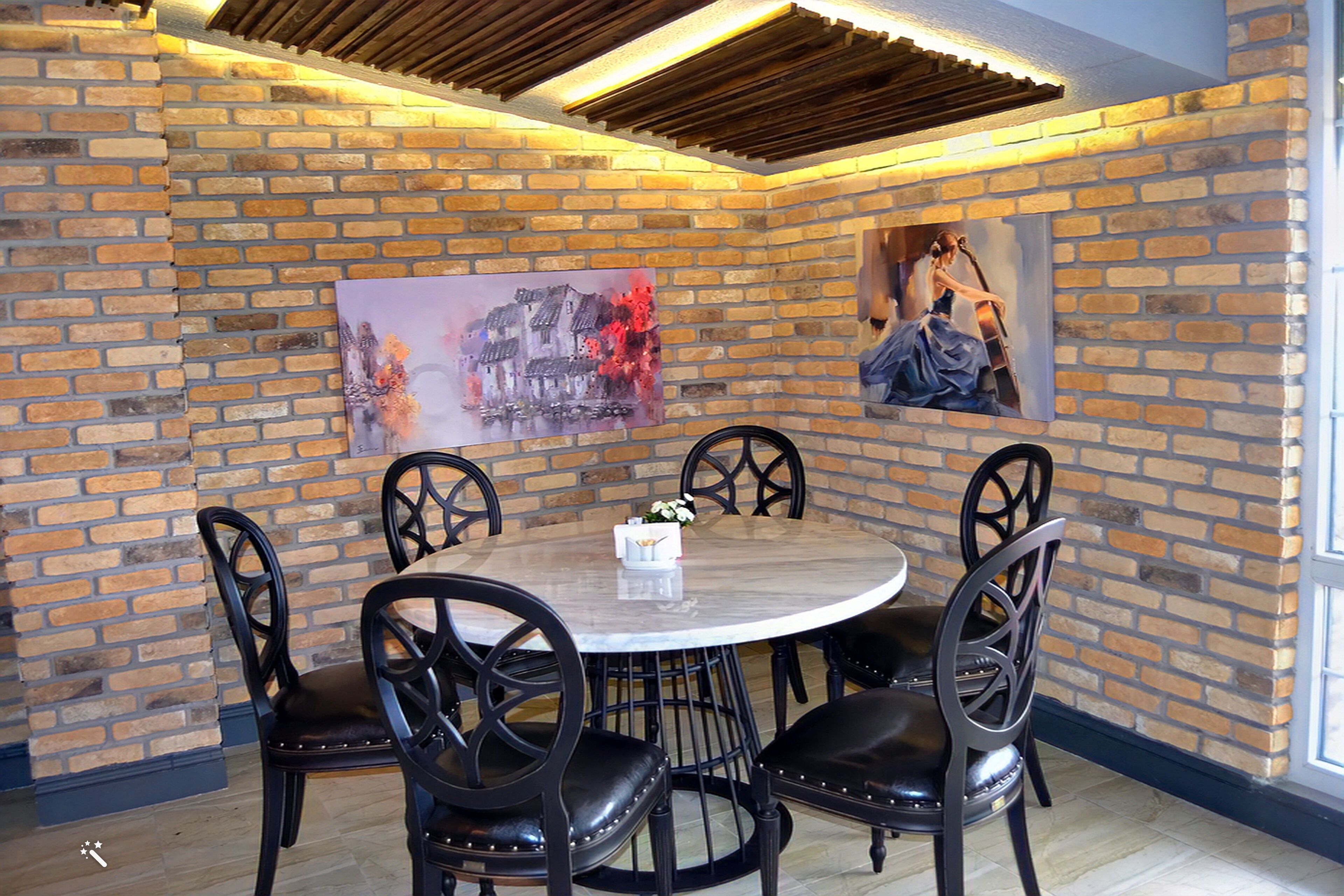 Un comedor con pared de ladrillo, una mesa redonda y sillas negras.