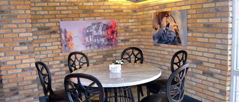 Un comedor con pared de ladrillo, una mesa redonda y sillas negras.