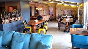 A restaurant with a brick wall, wooden ceiling, and blue upholstered furniture. - Hotel Zade (Erzurum)